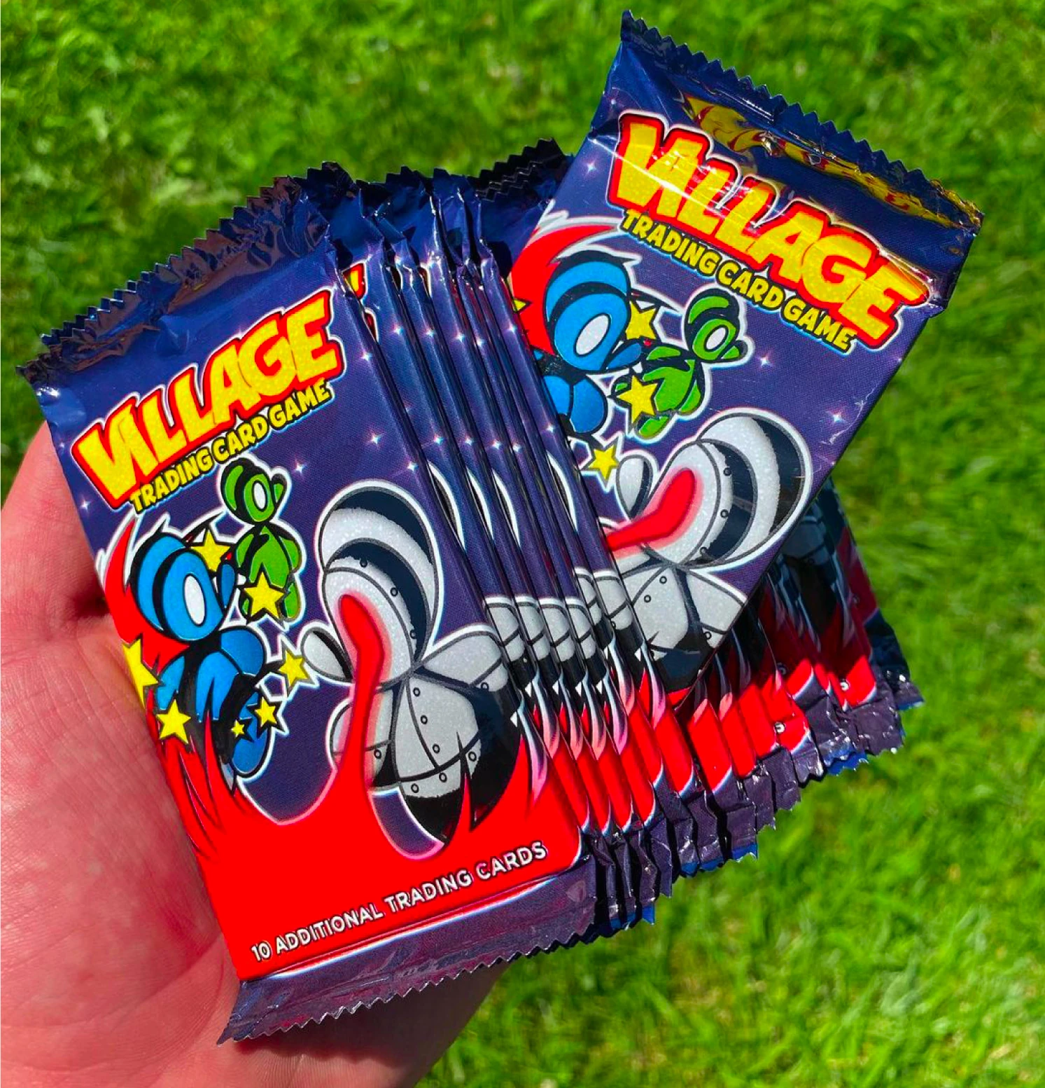 Village Mice foil trading card packs held over grass